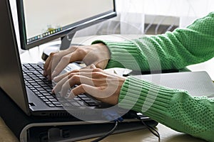 Close-up of male hands over black keyboard of laptop during typing