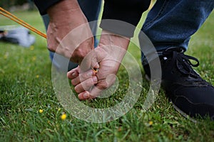 Close up of male hands pegging down a tent on grass.