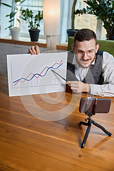 Close up male hands with pen pointing on business chart and mobile phone. People working with charts. Stock market