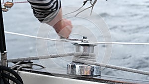 Close up of male hands pulling rope of sailboat, Yachtsman hands dealing with yacht ropes on halyard winch, Rope hauling