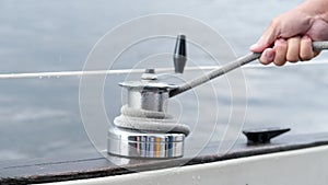 Close up of male hands pulling rope of sailboat, Yachtsman hands dealing with yacht ropes on halyard winch, Rope hauling