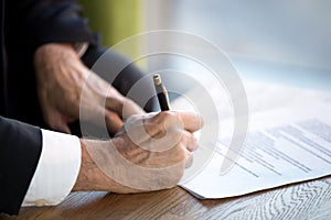 Close up male hands puts his signature on official document