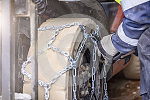 Close-up of male hands putting chains on a wheel. Examples of installing an anti-skid chain on a wheel in winter