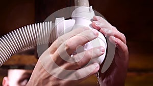 Close up of male hands repairing a leaking siphon in the kitchen or bathroom