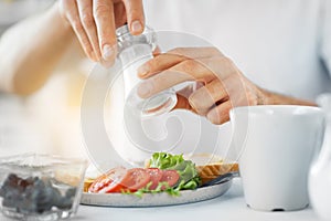 Close up of male hands seasoning food by salt mill