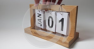 Close-up of male hands setting the date on a perpetual calendar, turning over the paper with month and number. It is the