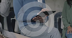 Close-up of male hands therapist writing notes while patients sitting in circle gesturing