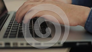 Close up male hands typing on keyboard blurry background. Fingers on keyboard. Camera is moving