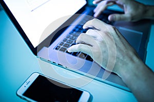 Close up of male hands typing on keyboard with white screen in the night