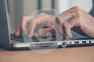 Close up of male hands typing laptop computer keyboard