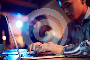 Close-up of male hands typing on laptop. Employees attending business meeting, conference. Blurred background with