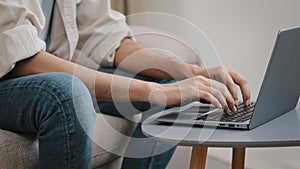 Close-up male hands typing on laptop keyboard. Unrecognizable guy unknown business man in jeans casual shirt sitting on