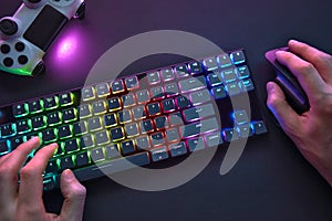 Close-up of male hands using color backlighted keyboard and mouse