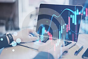 Close up of male hands using laptop computer with glowing forex chart on blurry office background. Trade, finance and money