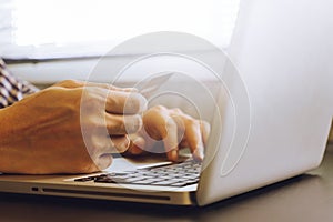 Close up of male hands using Laptop and holding credit card on the desk.