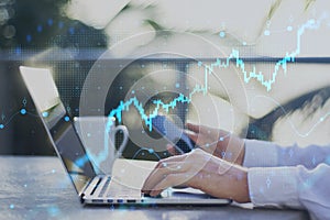 Close up of male hands using laptop and smartphone on desktop with coffee cup, growing forex chart and dot map on blurry outside