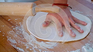 Close up male hands using rolling-pin flatten dough making pizza