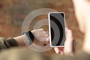 Close up of male hands using smartphone and smartwatch, education and business concept, blank screen