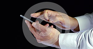 Close - up of male hands in white shirt electronic gadget phone with touch screen scrolling and tapping on black