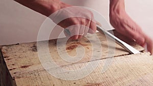 Close-up. Male hands with a wide screwdriver or other mounting tool open a wooden box. Breaking the first plank. Light background.