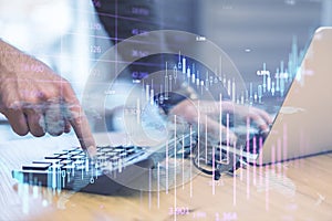 Close up of male hands workiing at office desktop with devices, calculator and glowing candlestick forex chart on blurry