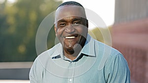 Close up male happy smiling toothy face. Portrait in city outdoors African American mature senior man ethnic middle-aged