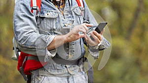 Close up male hiker hands using mobile phone.