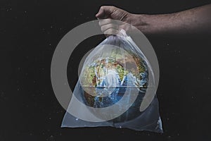 Close up male hold in plastic bag Earth world globe on black background. Save planet, planet is choking on plastic.. Stop nature