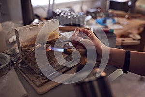 Close Up Of Male Jeweller Working On Ring With Blowtorch In Studio