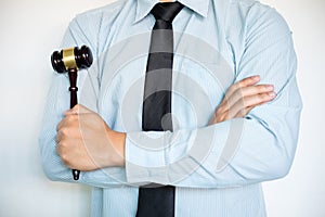 Close-up of Male lawyer with arm crossed standing front background and action hammer or gavel in hand