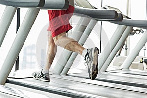 Close up of male legs running on treadmill in gym