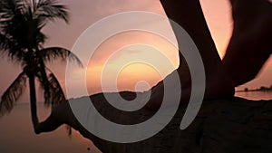 Close up of male legs. Young man walking on a palm tree at tropical beach during beautiful sunset. Slow motion