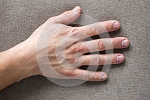 Close-up of male masculine hand with rough skin and short fingernails resting on flat copy space background, top view. Manual