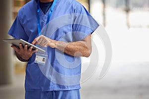 Close Up Of Male Medical Worker In Scrubs With Digital Tablet In Hospital