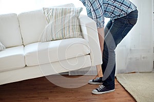 Close up of male moving sofa or couch at home