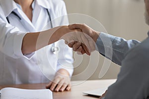 Close up of male patient handshake female doctor