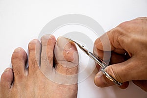 Close-up male pedicure with white background isolator photo of hand man nails and scissors