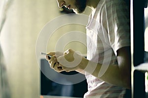 Close up male person lean on wardrobe and using phone at home d