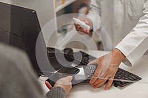 Close up of male pharmacist selling medications at drugstore to a woman customer