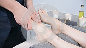 Close-up of a male physiotherapist doing foot massage to a young girl in a beauty and health spa. Foot and body care