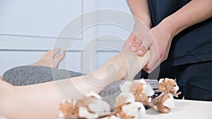 Close-up of a male physiotherapist doing foot massage to a young girl in a beauty and health spa. Foot and body care