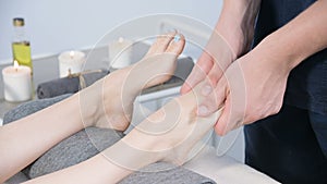 Close-up of a male physiotherapist doing foot massage to a young girl in a beauty and health spa. Foot and body care