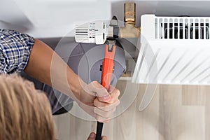 Male Plumber Fixing Thermostat Using Wrench