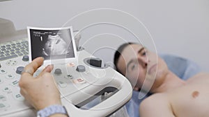 Close up of male radiologist operating ultrasonic machine with sonography print on keypad