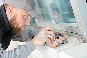 close-up male repairman fixing window with screwdriver