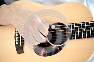 Close up of male`s fingers  placed on sound hole of the acoustic guitar for practicing in playing guitar