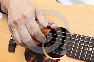 Close up of male`s fingers  placed on soundhole of the acoustic guitar for practicing in playing guitar