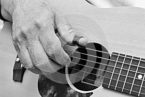 Close up of male`s fingers  placed on soundhole of the acoustic guitar for practicing in playing guitar. Black and white tone