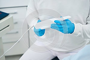 Close-up male stomatologist holding and showing dental intraoral camera