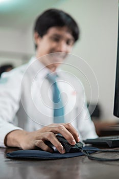 close up of a male student's hand sitting holding a computer mouse while studying